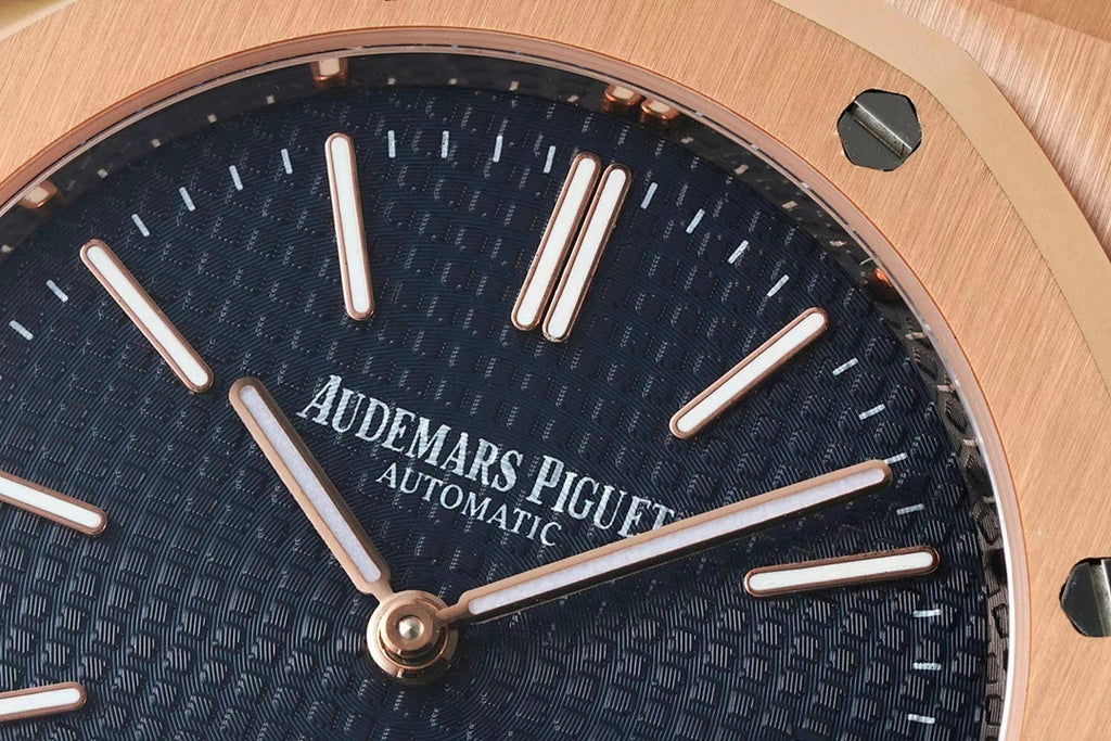 Dark blue wristwatch dial close-up with baton hands and 'AUTOMATIC' text.