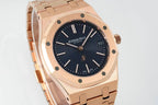 Rose gold-tone wristwatch close-up with dark blue dial, baton markers, and bezel details.
