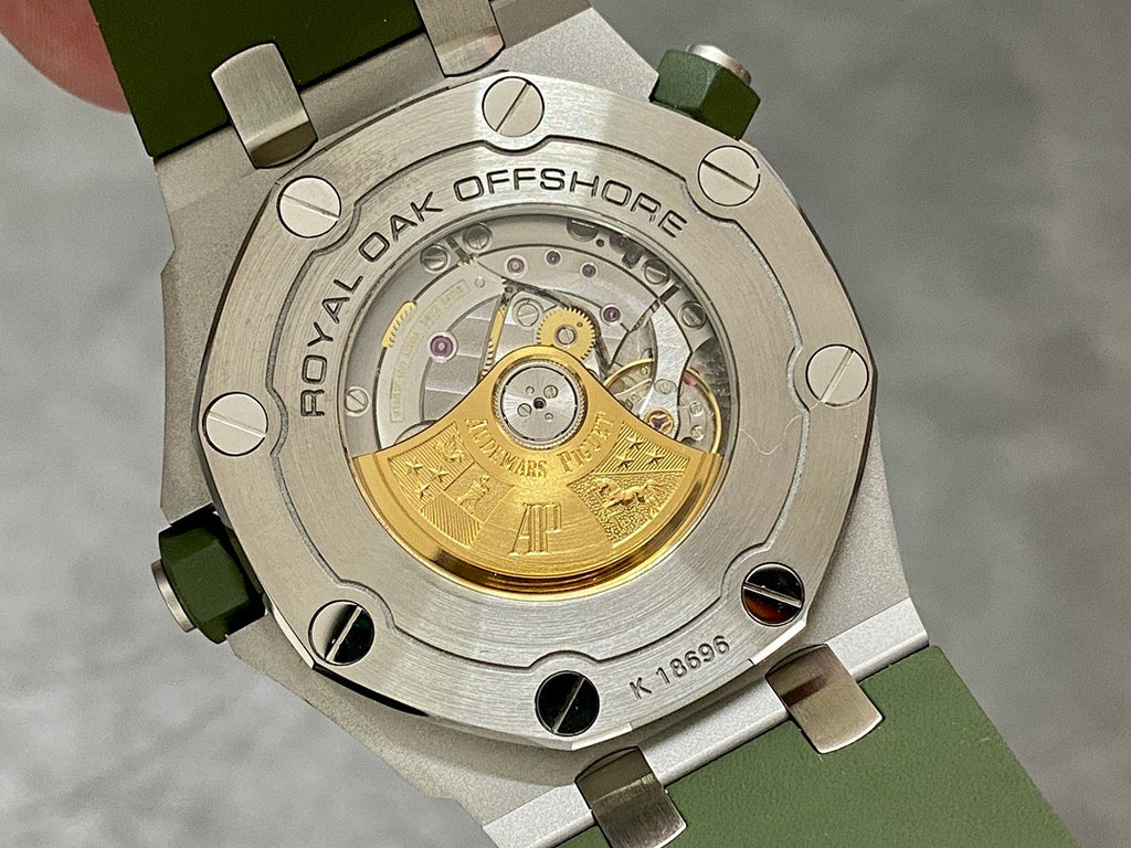 Audemars Piguet watch caseback showing a gold-toned movement on green strap