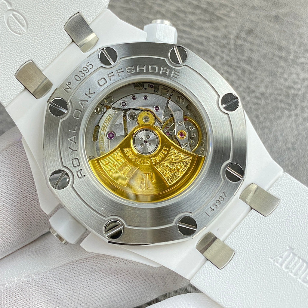Stainless watch caseback with exposed gold-toned movement under clear cover.