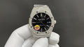 Audemars Piguet watch, black dial, stainless-steel bracelet, held by white-gloved hand