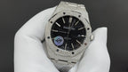 Audemars Piguet watch with black textured dial, metal bracelet, held in white gloves