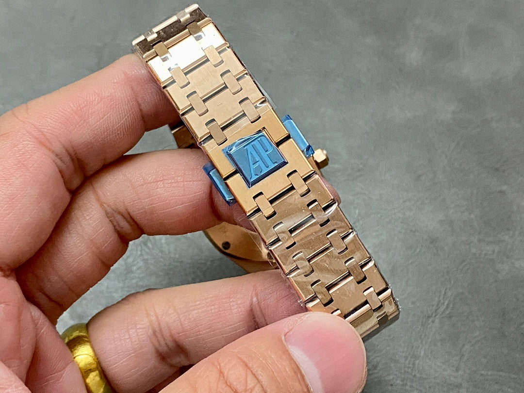 Gold-tone bracelet clasp with blue emblem on a metal link band