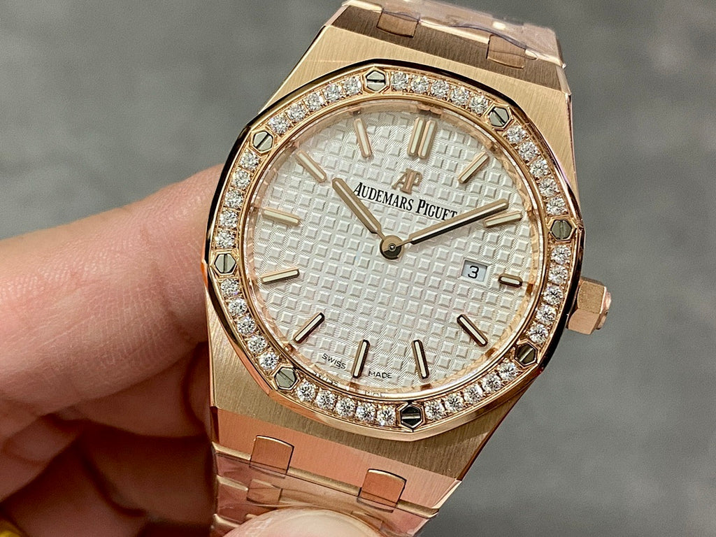 Gold-tone wristwatch with diamond bezel, textured white dial, and metal bracelet