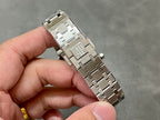 Luxury steel watch bracelet with engraved clasp panel, held in hand