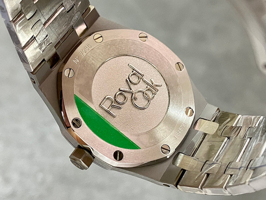 Steel watch caseback with circular emblem and green accent stripe