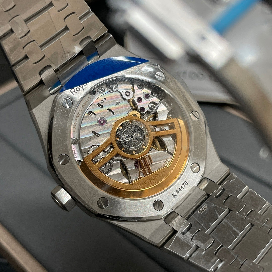 Skeleton-style watch movement window with gold balance on steel case and bracelet