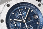 Blue chronograph dial close-up with tachymeter ring, subdials, and white indices