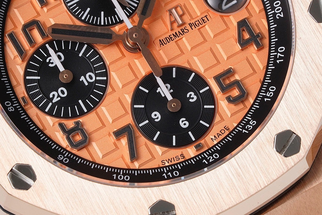 Rose gold-tone chronograph dial close-up with orange numerals and black counters