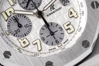 Close-up of white dial with Arabic numerals, subdials, and black hands