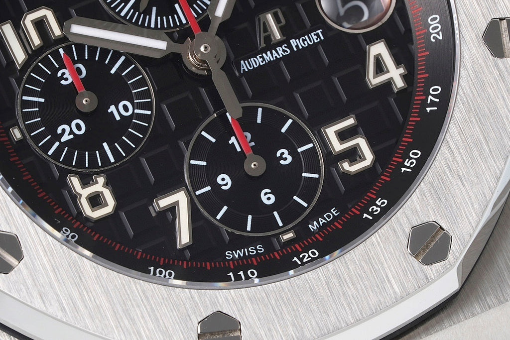 Black dial chronograph watch with red accents, tachymeter ring, and Arabic numerals