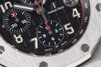 Black dial chronograph watch with red accents, tachymeter ring, and Arabic numerals