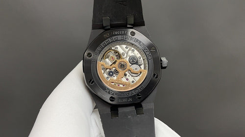 Audemars Piguet watch caseback with visible movement, black rubber strap, steel case