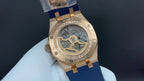Audemars Piguet Royal Oak watch case back, gold with visible movement, blue strap.