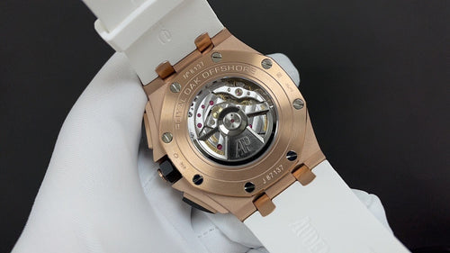 Luxury sport watch caseback in rose gold with visible movement, on white strap