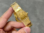 Gold-tone luxury wristwatch on metal bracelet, angled side view in hand