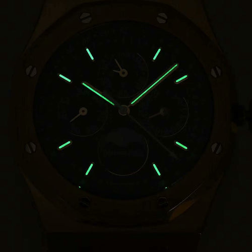 Wristwatch face with dark blue dial and glowing green markers and hands