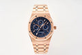 Rose gold-tone wristwatch with blue dial and three subdials, on matching bracelet.