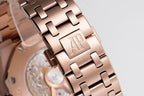 Rose-gold metal bracelet with engraved AP logo clasp detail.