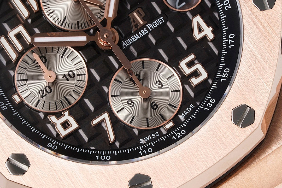 Black dial watch close-up with tachymeter scale, rose hands, and large date window