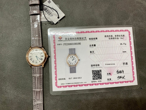 Cartier round wristwatch with gray leather strap beside warranty card