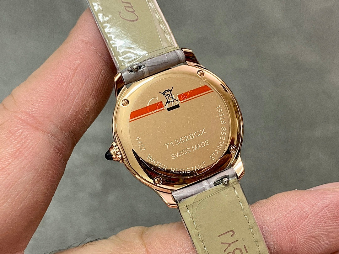 Gold-tone watch case back with engraved details, light green leather strap