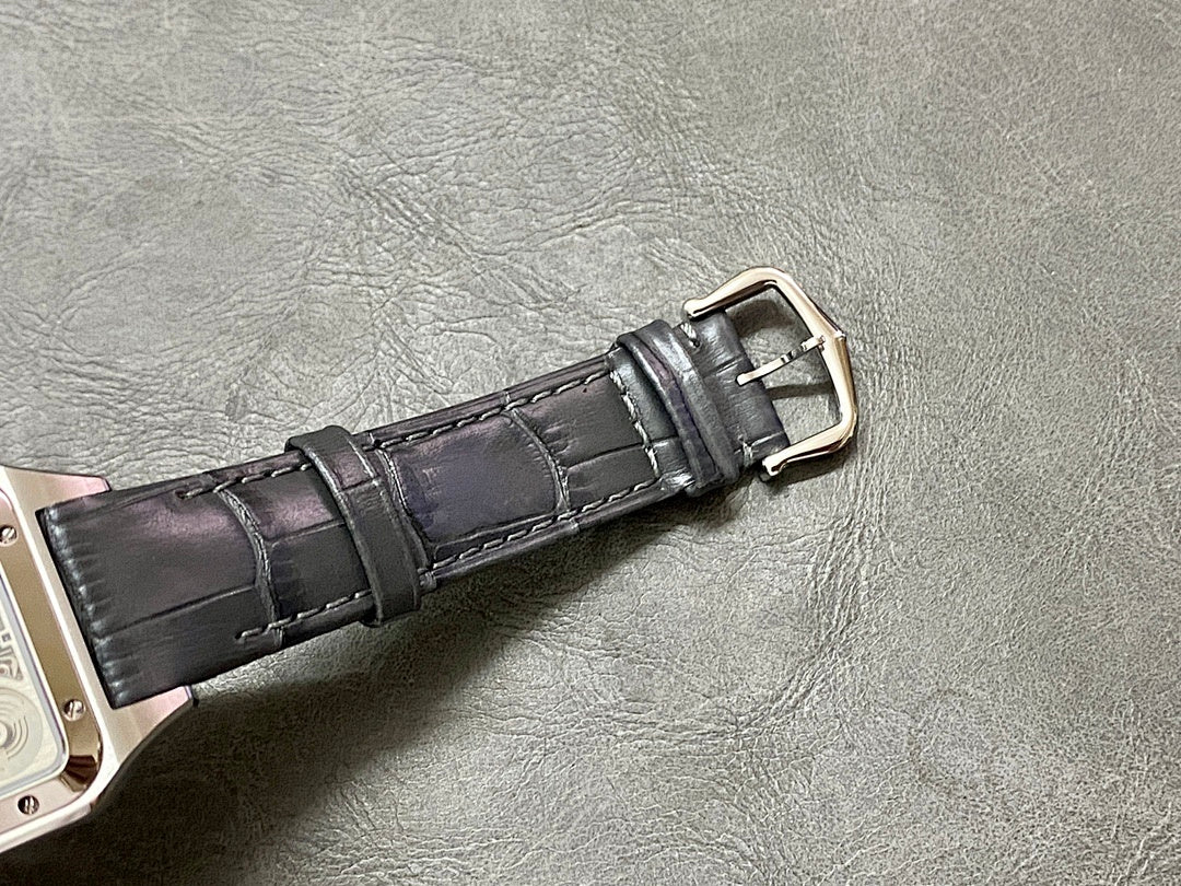 Black leather watch strap with silver-tone buckle connected to a square case