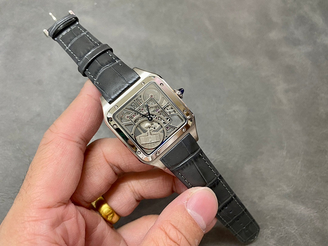 Square skeleton watch on black leather strap held in hand; silver-tone case visible