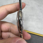 Silver-tone watch case side with polished bezel and black leather strap; thin profile.