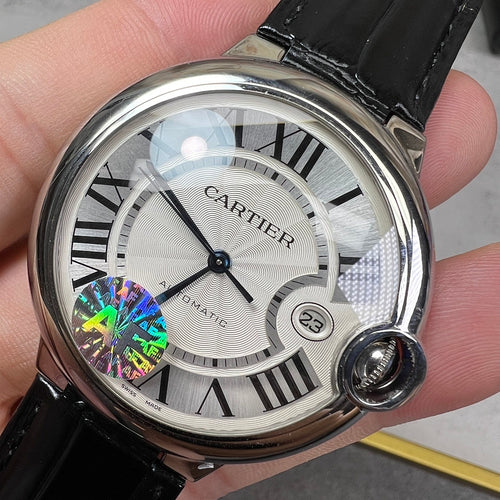 Round wristwatch: silver-tone case, black leather strap; white dial with Roman numerals.