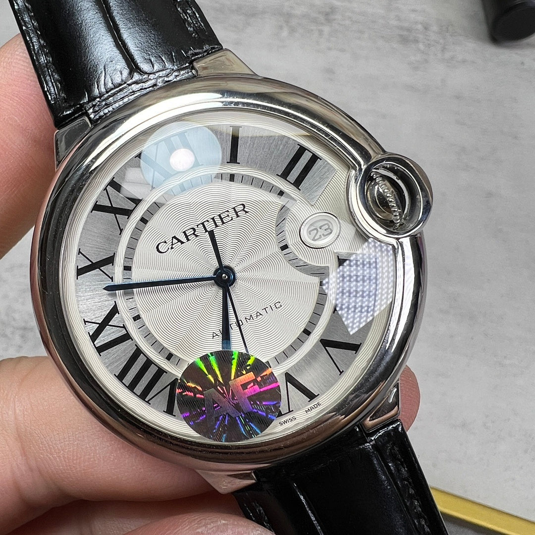 Round wristwatch dial close-up: white face with Roman numerals, black hands, colorful AF mark.