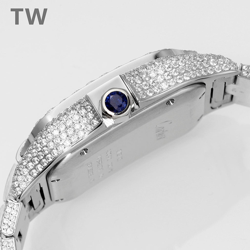 Diamond-encrusted wristwatch with blue gemstone crown, polished steel case, side view.