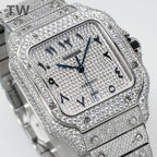 Cartier watch with diamond bezel, blue hands, black numerals, and metal link strap.