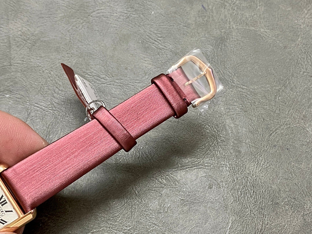 Burgundy leather watch strap with gold-tone buckle, keeper and stitching visible
