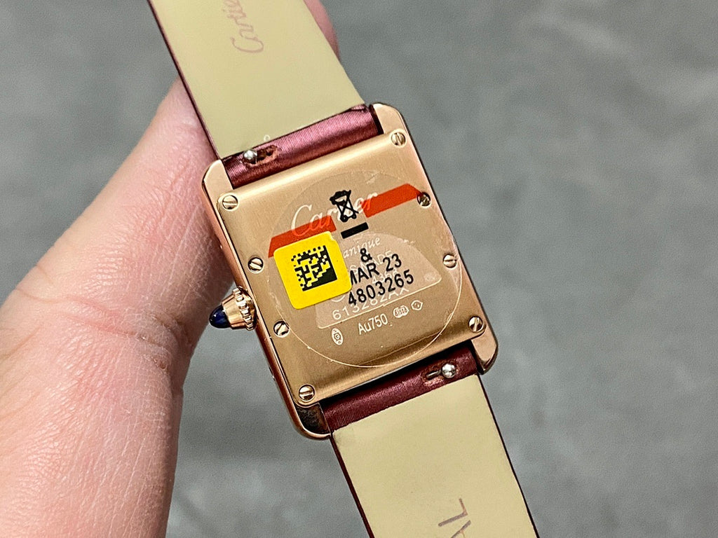 Gold-toned watch case back on burgundy leather strap, clasp and markings visible