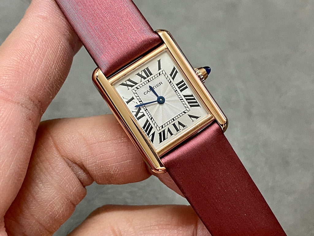 Rectangular wrist watch with burgundy leather strap, gold bezel, white dial with Roman numerals