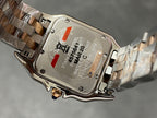 Two-tone watch case back with engraved text and bracelet clasp hardware