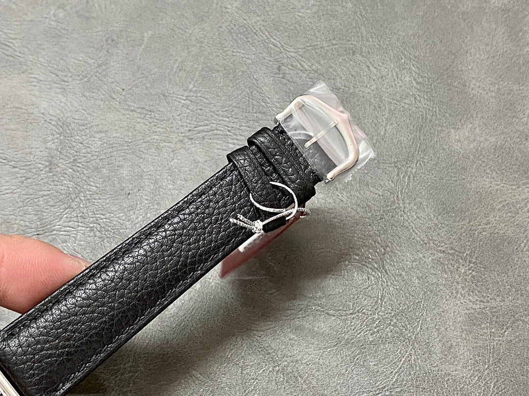 Black leather watch strap with metal buckle clasp and pin, shown from underside.