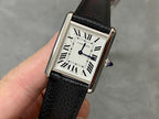 Cartier watch with black leather strap, rectangular silver case, white dial, Roman numerals.