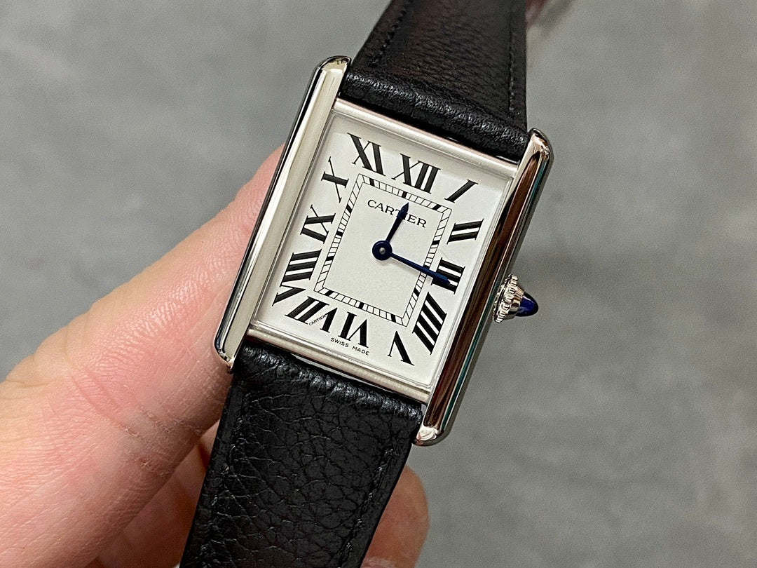 Cartier watch with black leather strap, rectangular silver case, white dial, Roman numerals.