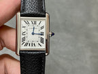 Rectangular watch on hand with black leather strap, silver frame, white dial and Roman numerals.