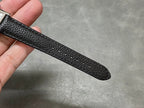 Black leather watch strap with pebbled texture, curved end band visible