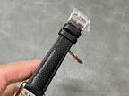 Black leather watch strap with buckle, clear protective cover over clasp