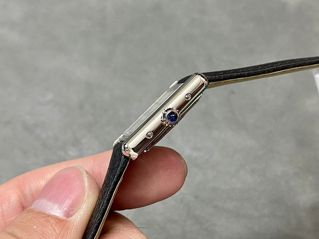 Cartier watch side profile with blue crown detail and polished metal case