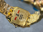 Gold Cartier watch case back with serial text and small red and blue details.