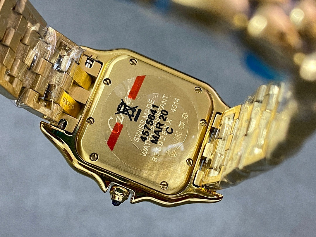 Gold Cartier watch case back with serial text and small red and blue details.