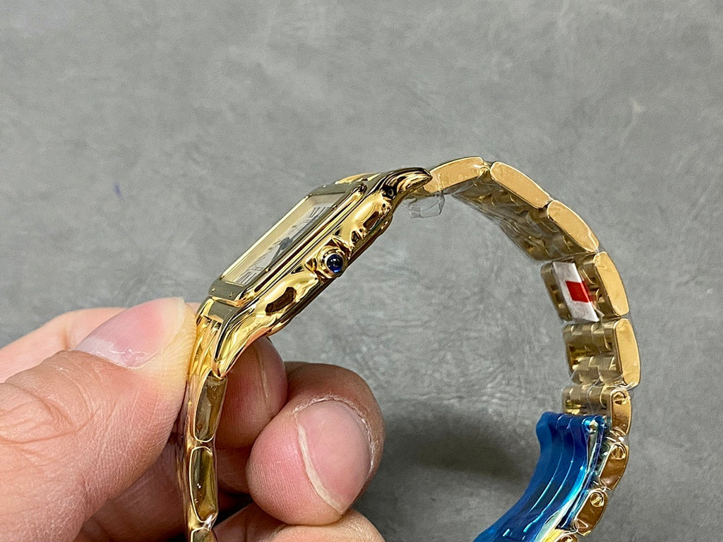 Gold Cartier watch side view with crown and blue gemstone accent.