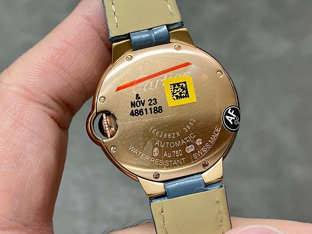 Back of Cartier watch in gold tone with case markings and blue leather strap