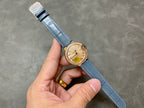 Cartier watch on blue leather strap with gold-toned case and cream dial