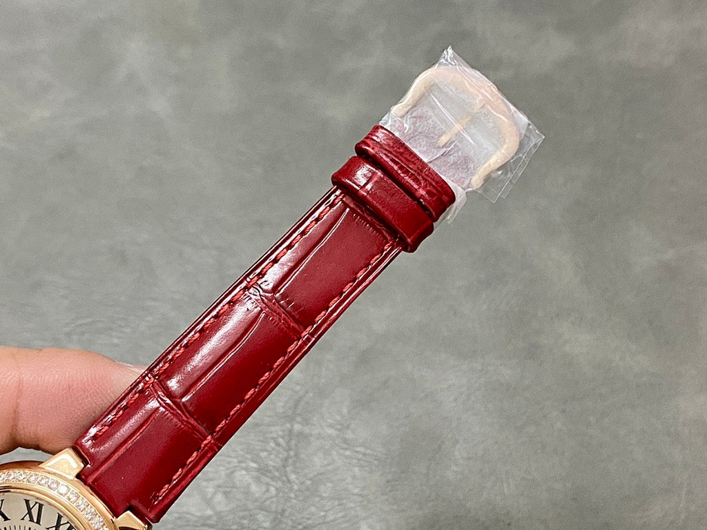 Red leather watch strap with gold-tone buckle and protective sleeve on clasp end